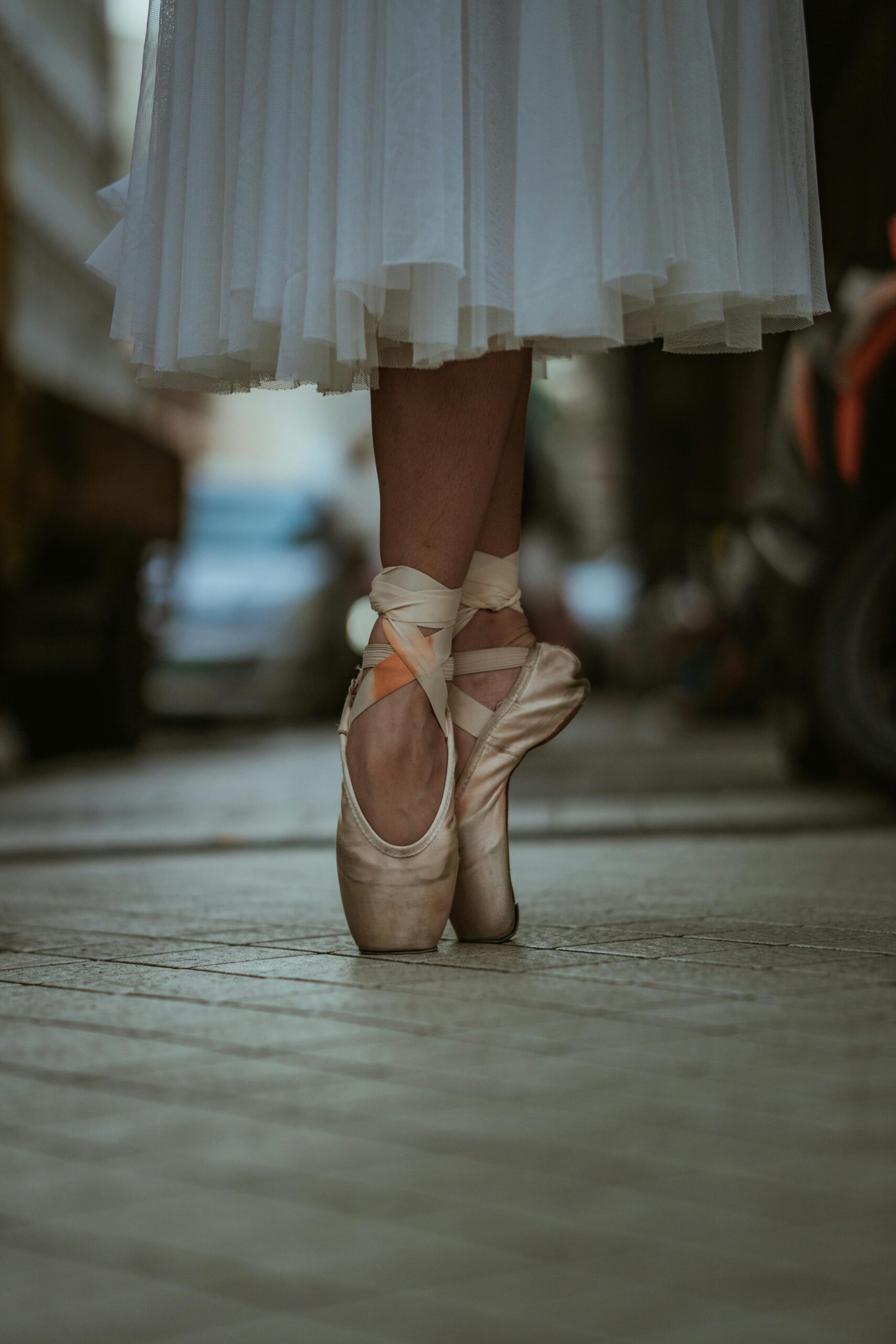 Ballet dancer in pointe shoes on urban street, showcasing elegance and balance.