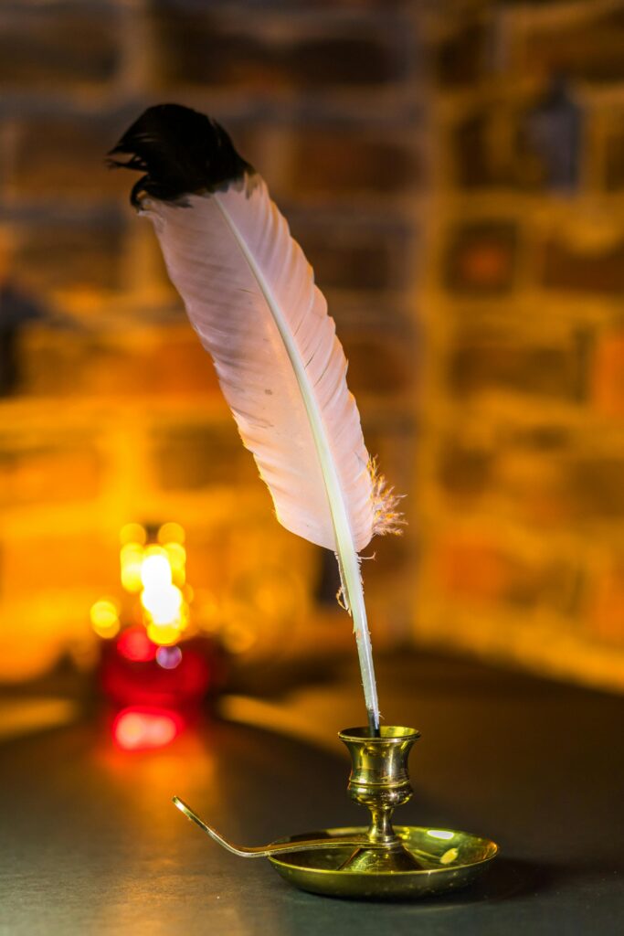 A classic quill pen in a brass stand against a warm, vintage backdrop. Perfect for historical themes.